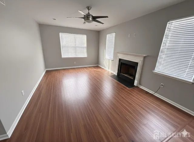 an empty room with wooden floor fireplace and windows