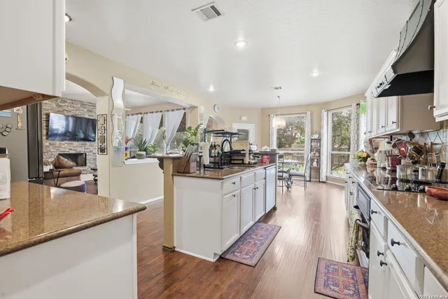 a kitchen with kitchen island granite countertop lots of counter top space and wooden floor