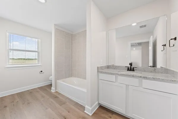 a bathroom with a granite countertop sink a mirror and a bathtub
