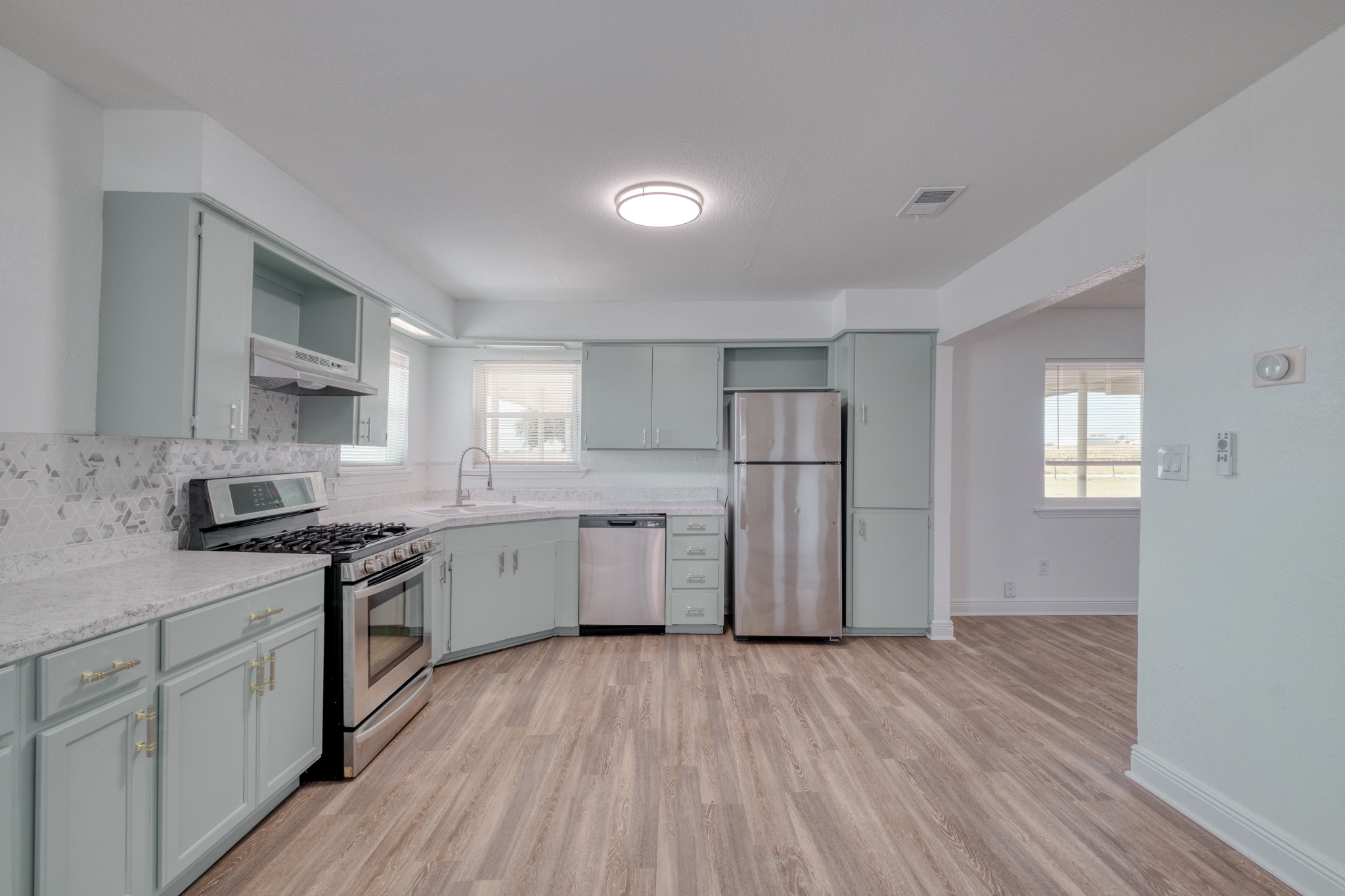 20960 Cameron Road Coupland, TX 78615 - Photo 6 of 21 Laminated flooring runs throughout this kitchen with stone counters and stainless steel appliances.