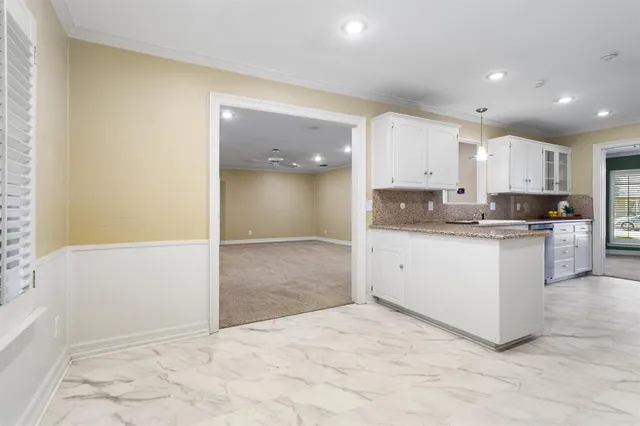 a large white kitchen with kitchen island a sink stainless steel appliances and cabinets
