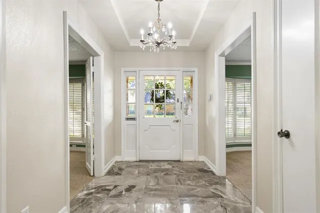 a view of a hallway with wooden floor and a chandelier