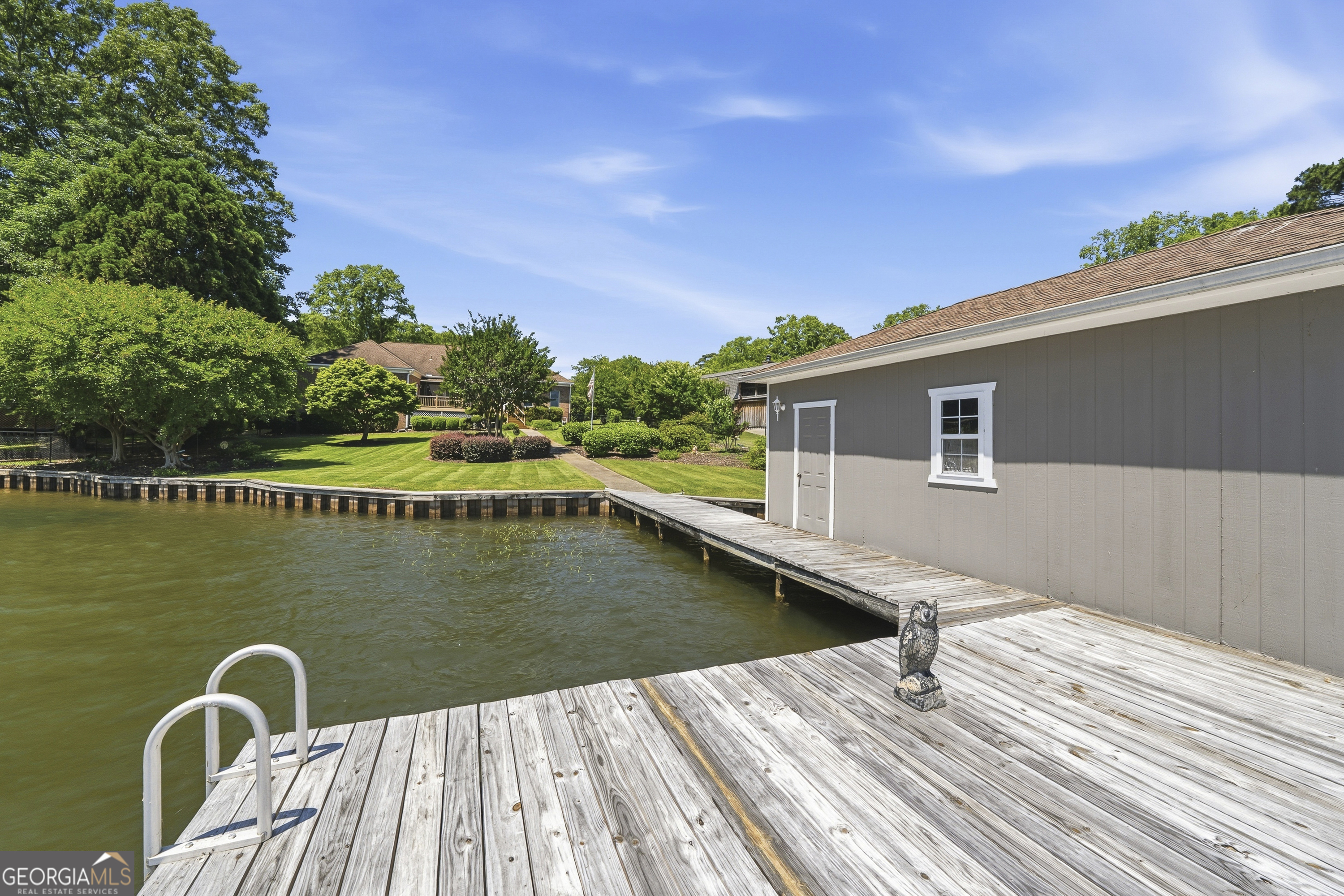 104 Spruce Point Southeast Eatonton, GA 31024 - Photo 43 of 63 a view of a wooden deck and lake with trees in the background