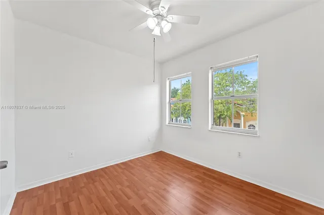 a view of empty room with window and ceiling fan