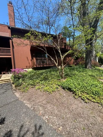 a view of a wooden house with a yard and plants