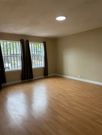 a view of an empty room with a window and wooden floor