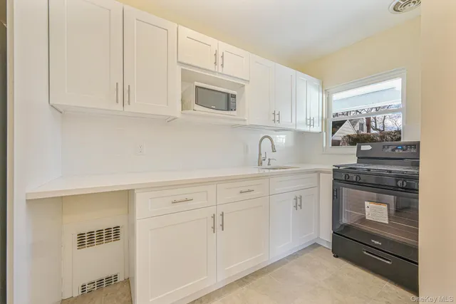 a kitchen with white cabinets and sink