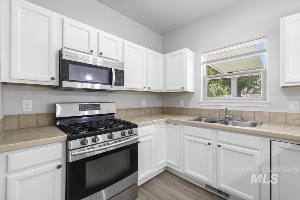 1183 Cortes Loop Twin Falls, ID 83301 - Photo 5 of 30 Bright kitchen featuring white cabinetry, light-toned countertops, and a tiled backsplash