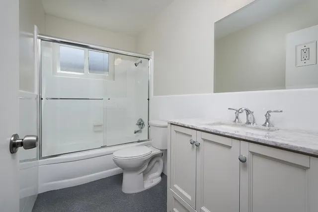 a bathroom with a granite countertop sink toilet and shower