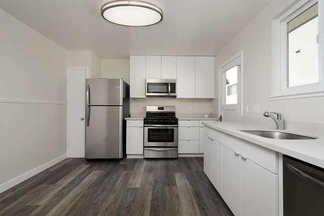 a kitchen with granite countertop a refrigerator stove top oven and sink