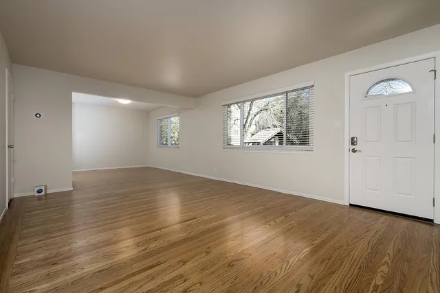 an empty room with wooden floor and windows