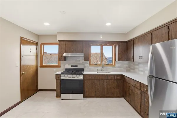 a kitchen with refrigerator a stove a sink and a window