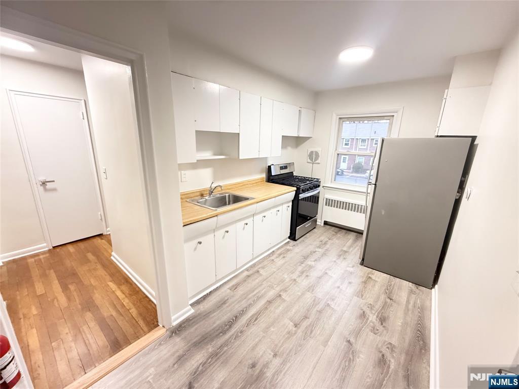 293 Bogert Road, Unit 1A River Edge, NJ 07661 - Photo 9 of 14 a kitchen with a refrigerator a stove and white cabinets with wooden floor