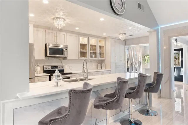a large white kitchen with a large counter top appliances and cabinets
