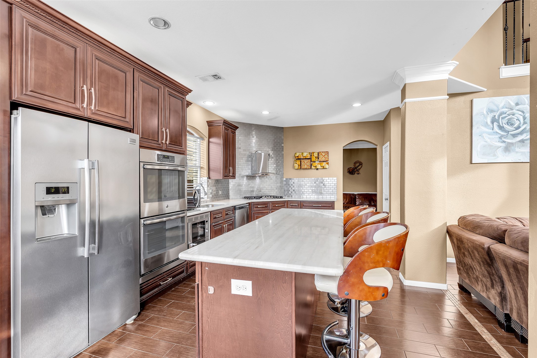 611 River Delta Lane Rosenberg, TX 77469 - Photo 21 of 39 a kitchen with stainless steel appliances a refrigerator a stove a sink a dining table and chairs with wooden floor