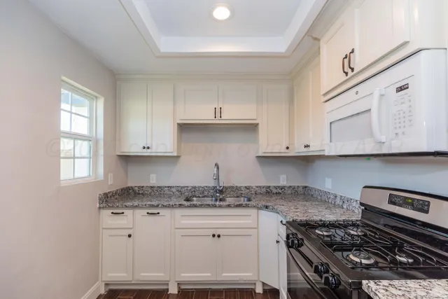 a kitchen with granite countertop a stove sink and cabinets