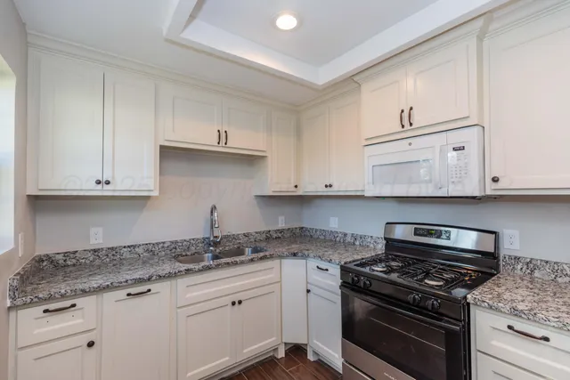a kitchen with granite countertop white cabinets and stainless steel appliances