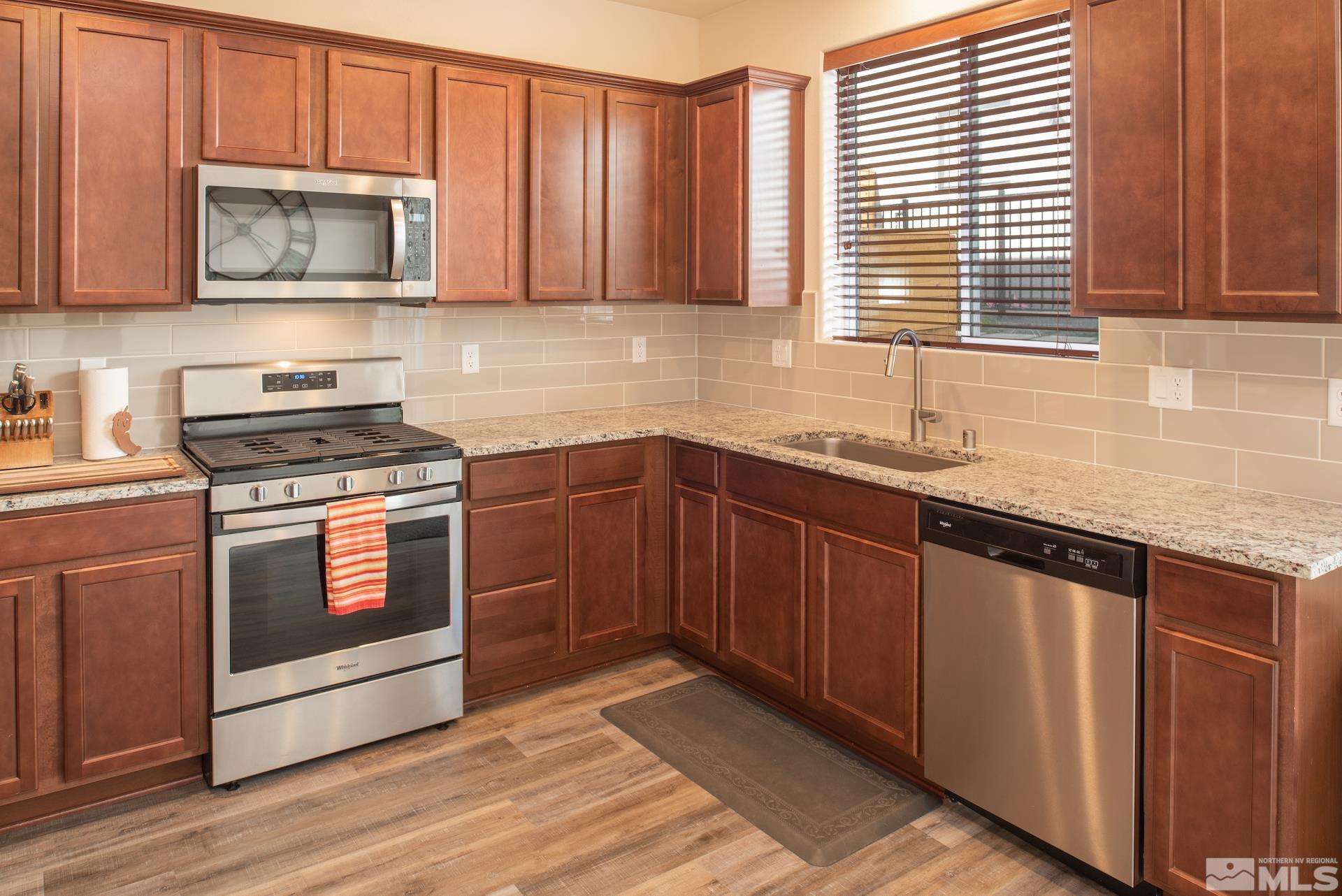 575 Logan Jacob Lane Reno, NV 89503 - Photo 9 of 31 a kitchen with granite countertop wooden cabinets stainless steel appliances and a sink
