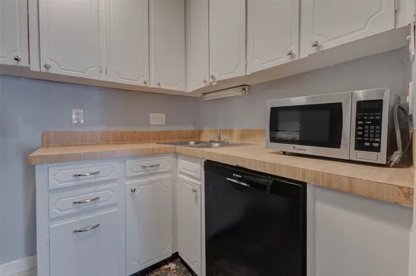 a kitchen with granite countertop white cabinets and black appliances
