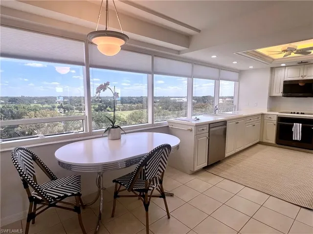 a dining hall with stainless steel appliances granite countertop a sink a stove a table and chairs