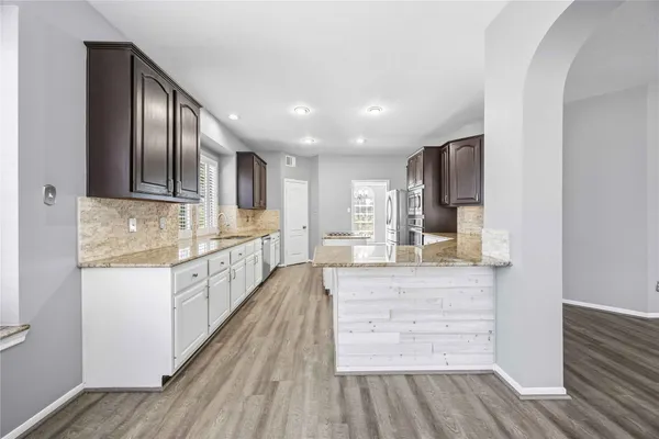 a large kitchen with granite countertop a large counter top space stainless steel appliances and cabinets