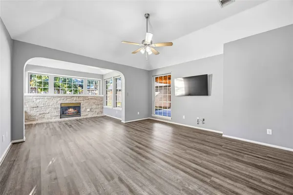 a view of an empty room with a window and wooden floor