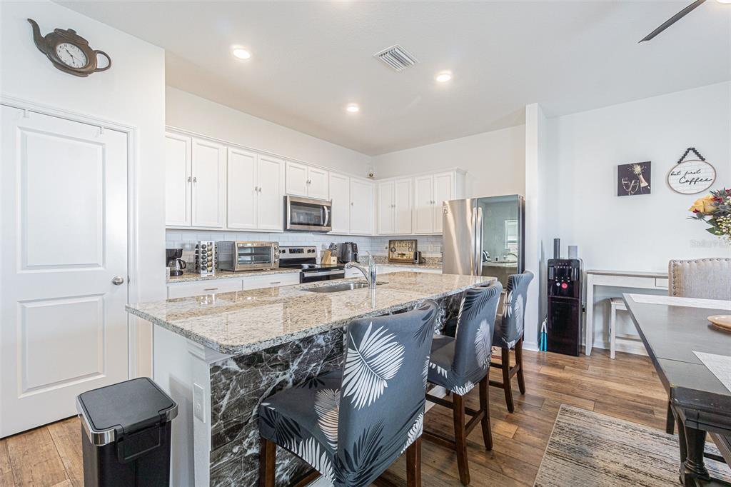 5265 Cricket Hill Road Brooksville, FL 34602 - Photo 14 of 30 a kitchen with stainless steel appliances granite countertop a table chairs sink refrigerator and cabinets