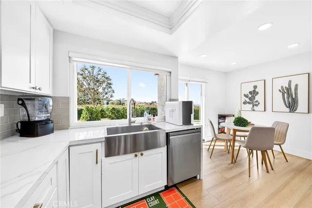 a kitchen with stainless steel appliances granite countertop a stove top oven a sink a dining table and chairs with wooden floor