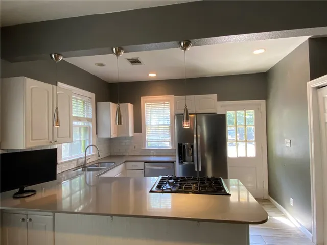 a kitchen with stainless steel appliances granite countertop a refrigerator a stove and white cabinets