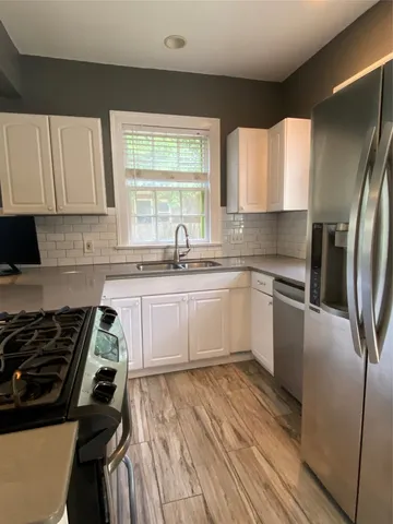 a white kitchen with sink and stainless steel appliances