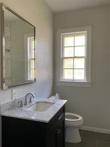 a bathroom with a granite countertop sink toilet and mirror