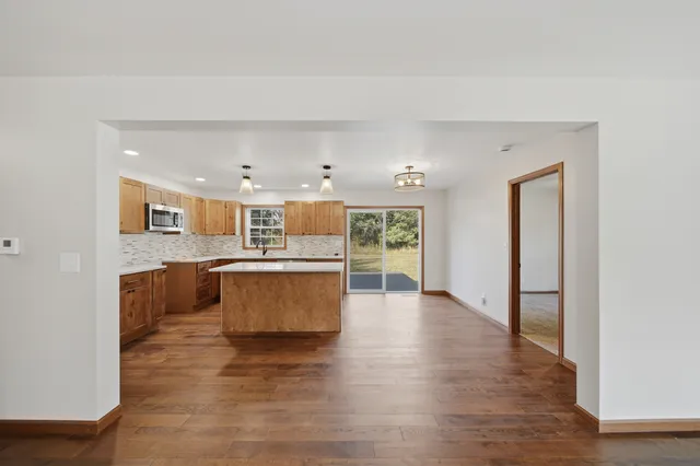 a large kitchen with stainless steel appliances a sink dishwasher a stove top oven a large window with wooden floor and cabinets