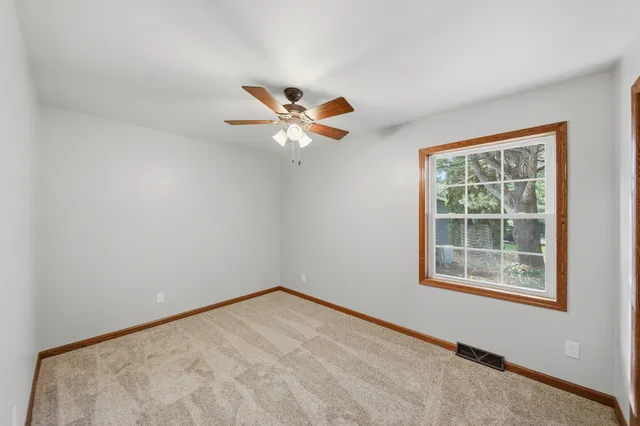 an empty room with window and ceiling fan