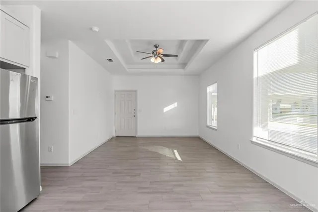 a view of empty room with wooden floor and fan