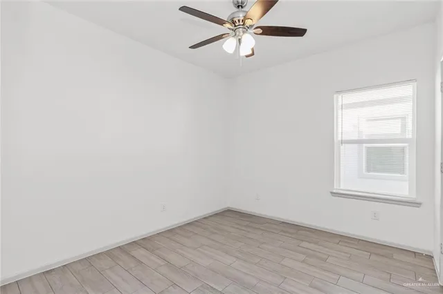 an empty room with a window and ceiling fan