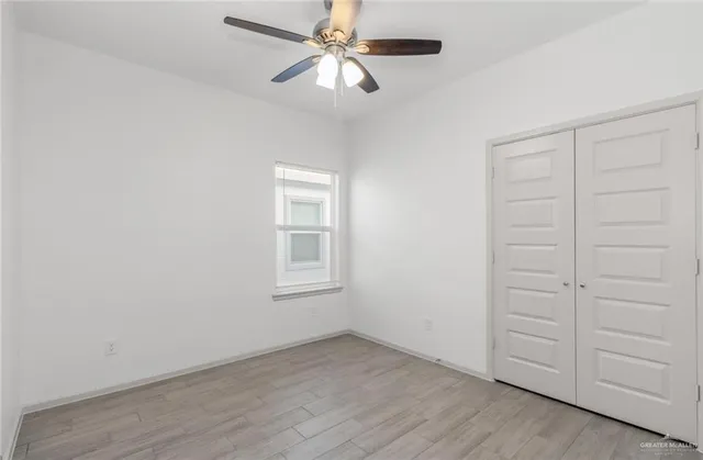 an empty room with windows and fan