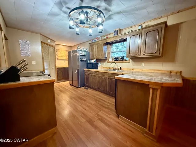 a kitchen with stainless steel appliances granite countertop a sink dishwasher stove and wooden cabinets