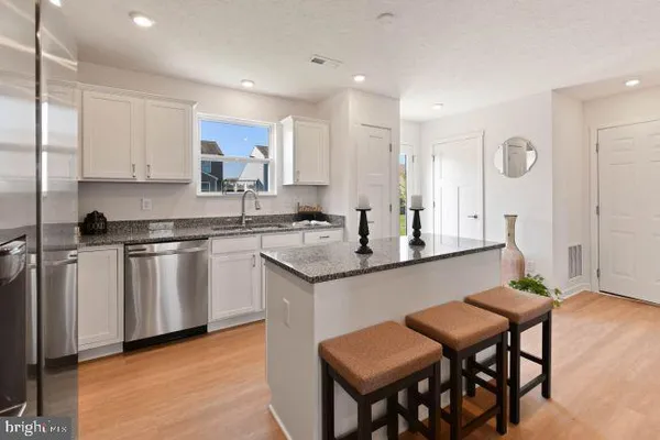 a kitchen with white cabinets and chairs