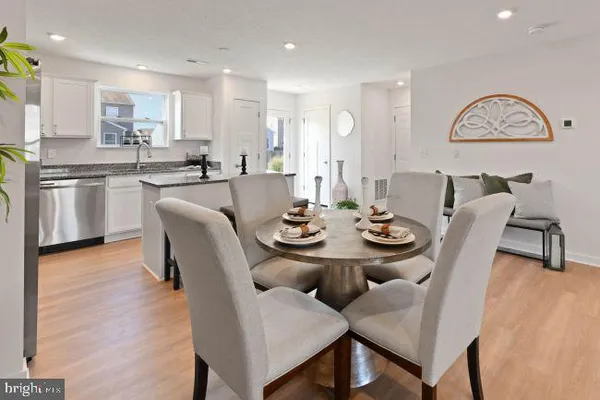 a dining room with stainless steel appliances kitchen island granite countertop furniture and wooden floor