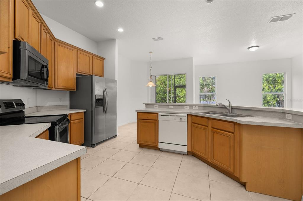 2172 The Oaks Boulevard Kissimmee, FL 34746 - Photo 25 of 81 a kitchen with stainless steel appliances granite countertop a stove a sink a refrigerator and a microwave
