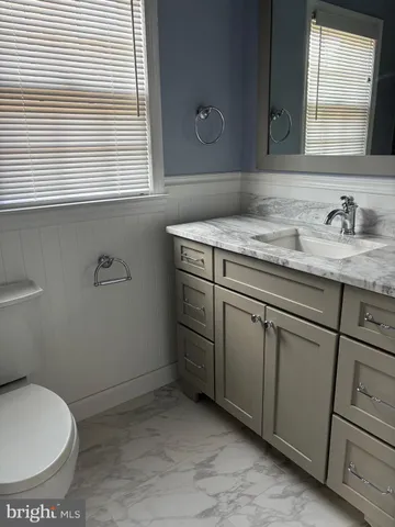 a bathroom with a granite countertop sink toilet and mirror