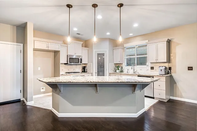 a kitchen with stainless steel appliances granite countertop a kitchen island a stove and a sink