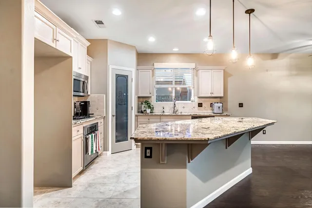 a kitchen with stainless steel appliances granite countertop a sink a stove and a refrigerator