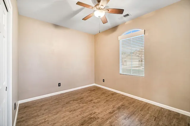 a view of an empty room with window and chandelier fan