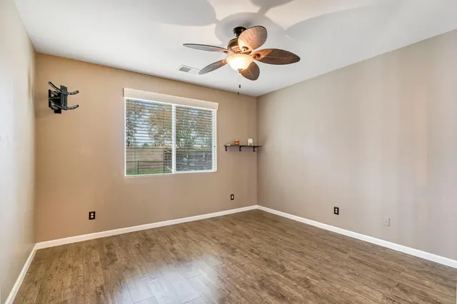 a view of an empty room with window and wooden floor
