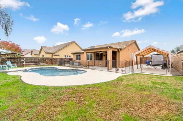 a view of a swimming pool with a yard and palm trees