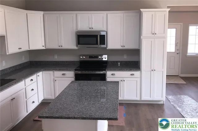 a kitchen with stainless steel appliances granite countertop a stove a microwave and a white cabinets