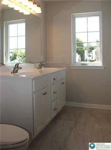 a bathroom with a granite countertop toilet a sink a window and mirror