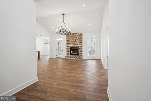 a view of an empty room with wooden floor and a chandelier