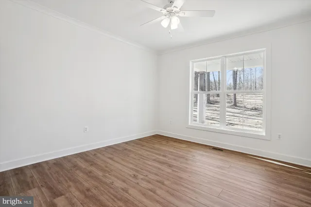an empty room with wooden floor chandelier and windows